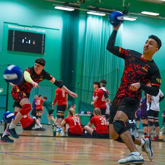 Boys playing dodgeball with girls playing in background