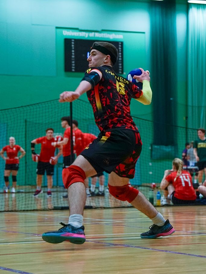 Man throwing ball at Surrey Dodgeball with girls and boys playing dodgeball in background