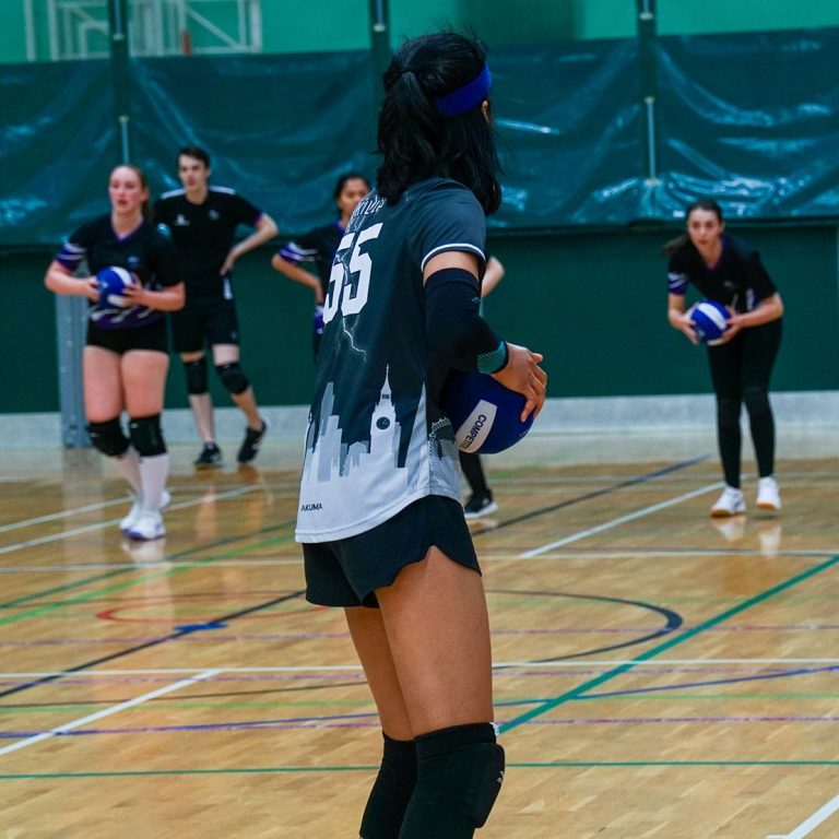 Girl holding ball at Surrey Dodgeball with girls playing dodgeball in background